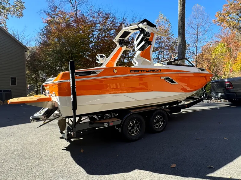 Slide: The Image of 2023 Centurion Ri230 boat in vibrant orange on a trailer, surrounded by autumn trees. - 13