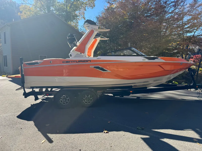 Slide: The Image of 2023 Centurion Ri230 boat in vibrant orange on a trailer, parked outdoors. - 14