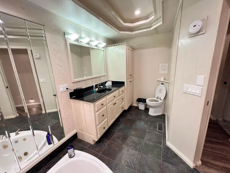 Slide: The Image of Modern bathroom with black countertop, large mirror, and tiled floor in Thoroughbred 99 x 20 model. - 17