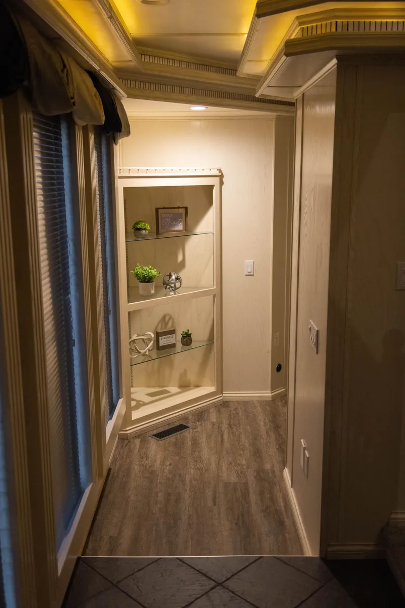 Slide: The Image of Hallway with decorative shelving, wood flooring, and ambient ceiling lighting in a Thoroughbred 99 x 20 model. - 21