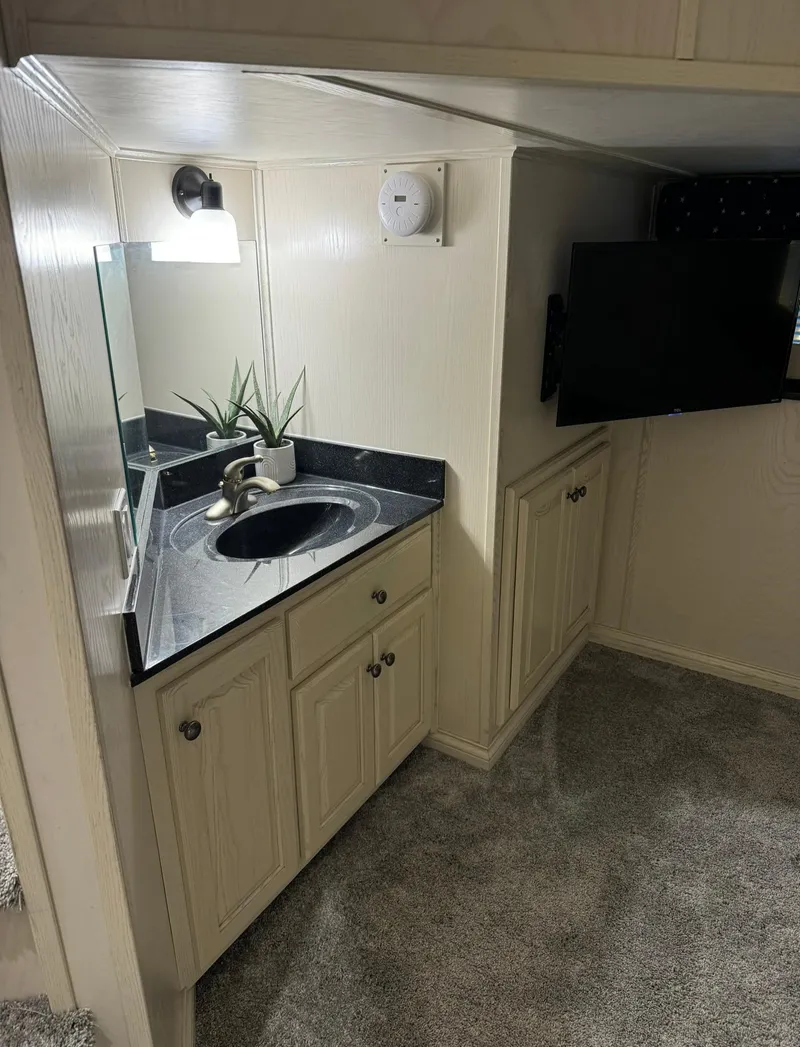 Slide: The Image of Compact bathroom with sink, mirror, and TV in a 2002 Thoroughbred 99 x 20 model. - 30
