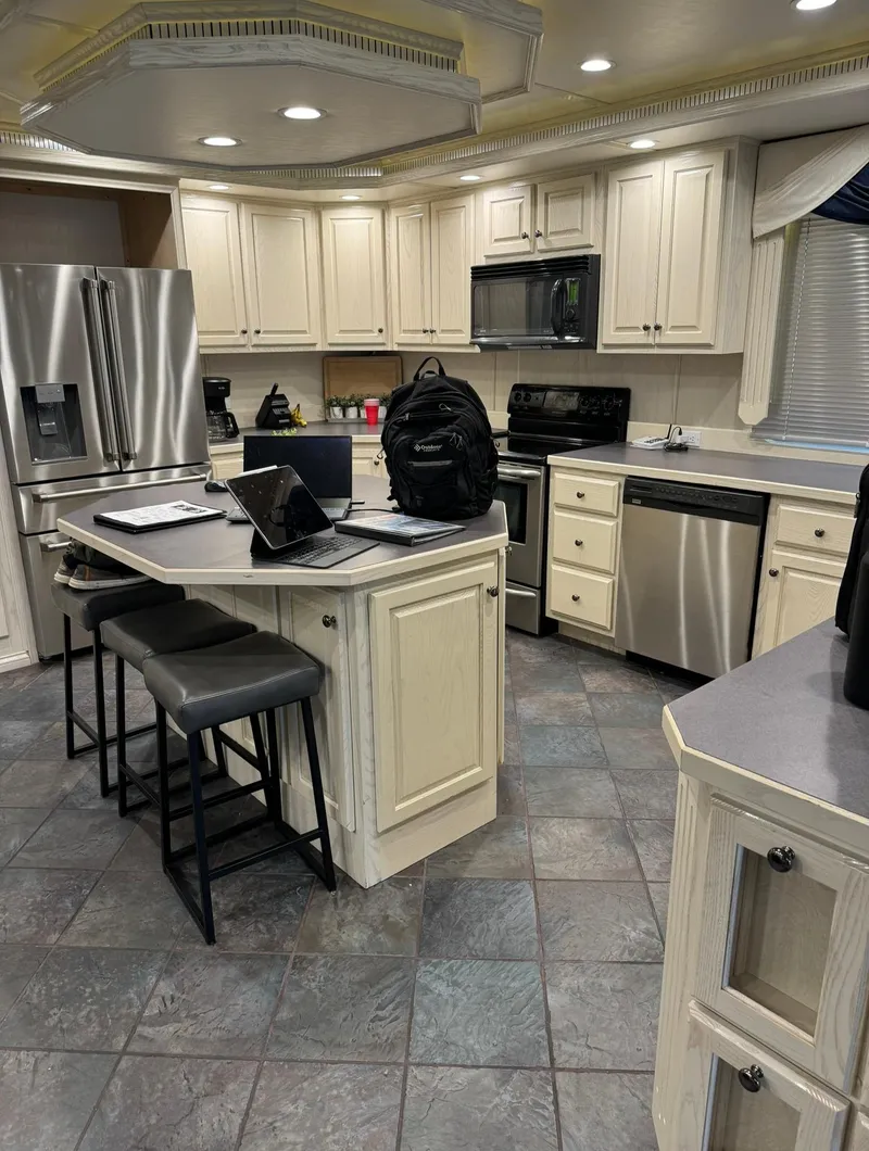 Slide: The Image of Modern kitchen with stainless steel appliances, island seating, and tiled flooring. - 43