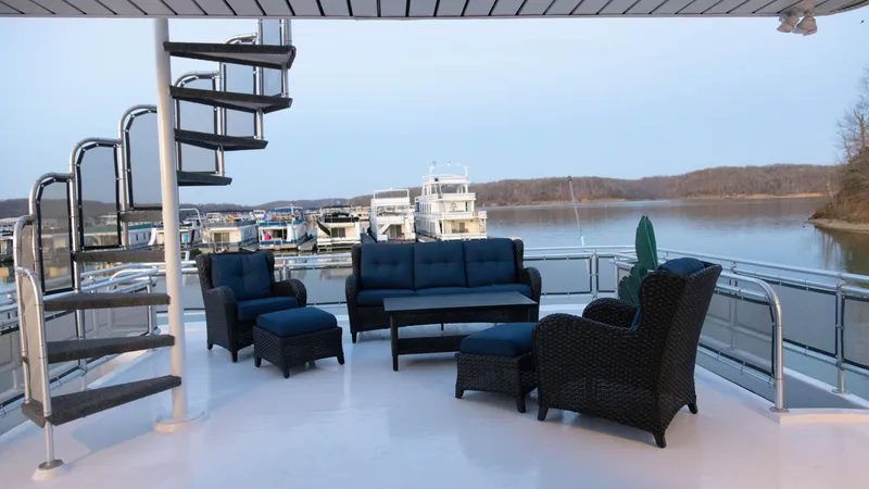 Slide: The Image of Luxurious Thoroughbred 99 x 20 yacht deck with elegant seating, spiral staircase, and scenic lake view. - 7