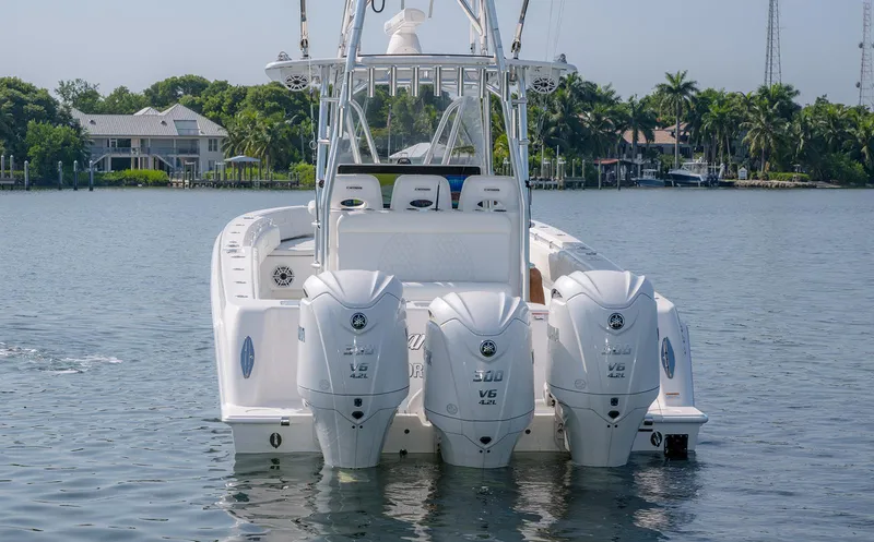 Slide: The Image of 2022 Contender 39 ST boat with triple outboard engines on a calm waterway. - 2