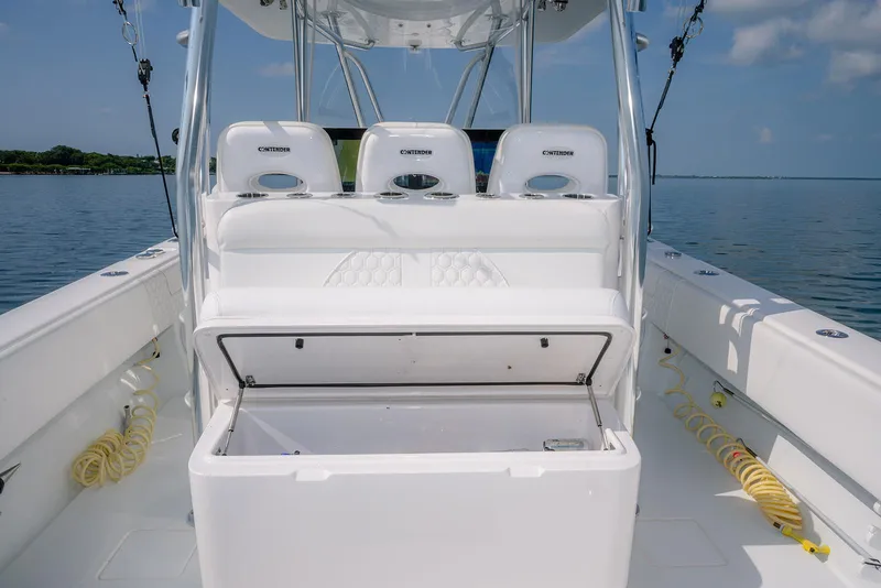 Slide: The Image of 2022 Contender 39 ST boat interior with open storage compartment, white seating, and ocean backdrop. - 6