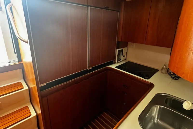 Slide: The Image of Compact kitchen area in a 1999 Tiara Yachts 43 Open, featuring wood cabinetry and modern appliances. - 16