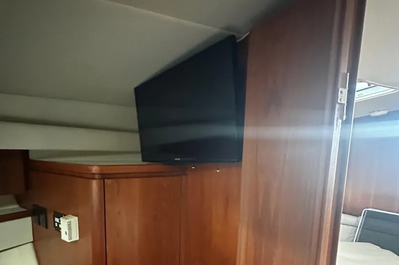 Slide: The Image of Interior of 1999 Tiara Yachts 43 Open with mounted TV and wooden cabinetry. - 22