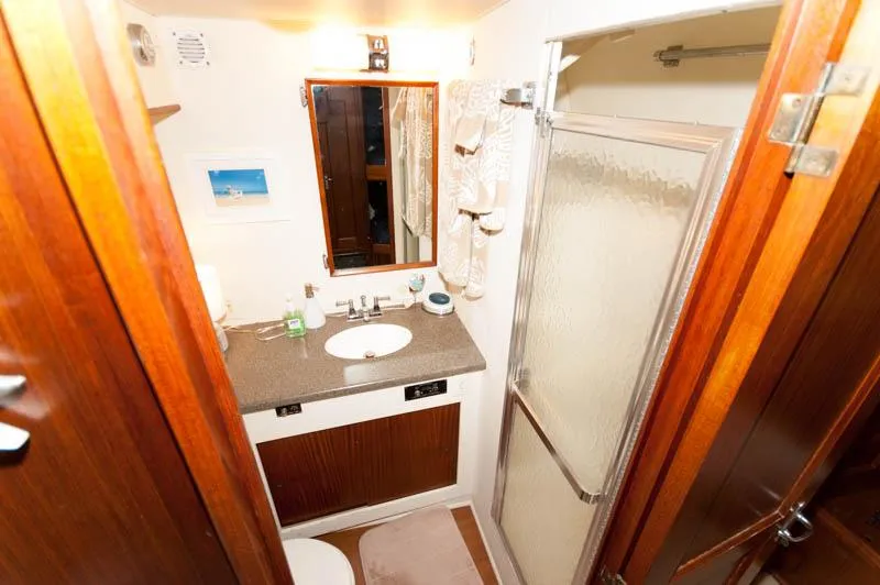 Slide: The Image of 1980 Hatteras 58 Motor Yacht bathroom with shower, sink, and wooden cabinetry. - 13