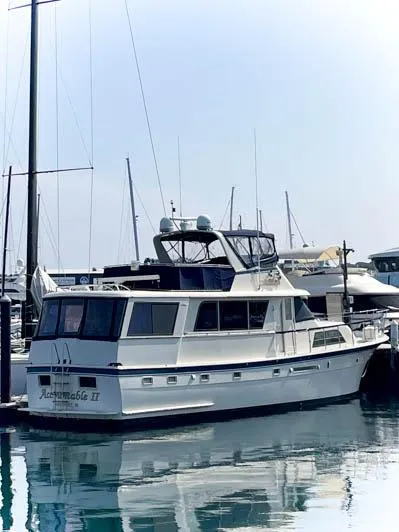 Slide: The Image of 1980 Hatteras 58 Motor Yacht docked in a marina, reflecting on calm water. - 3