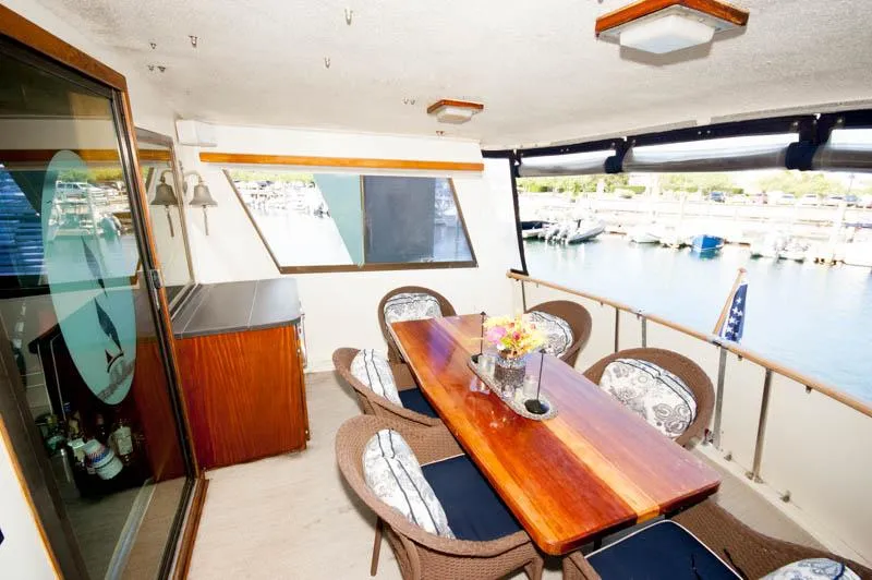 Slide: The Image of 1980 Hatteras 58 Motor Yacht aft deck with dining table, chairs, and marina view. - 33