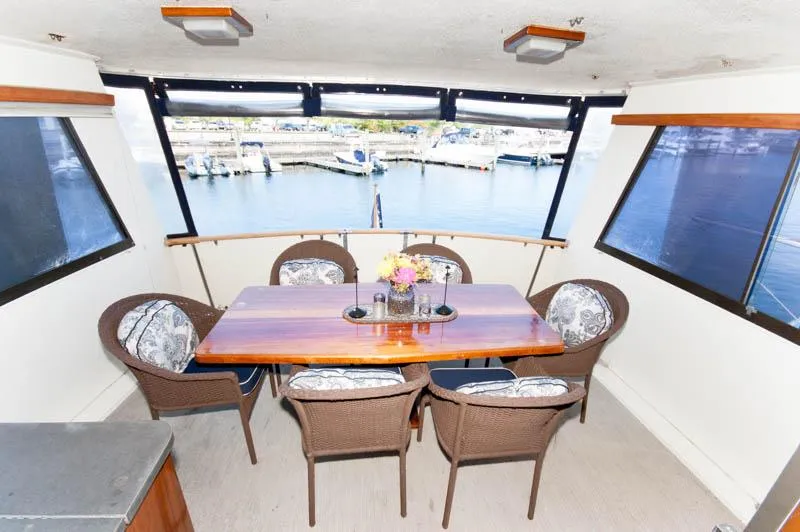 Slide: The Image of 1980 Hatteras 58 Motor Yacht dining area with table, chairs, and marina view. - 35