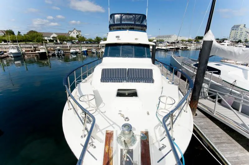 Slide: The Image of 1980 Hatteras 58 Motor Yacht docked in a marina under a clear blue sky. - 4
