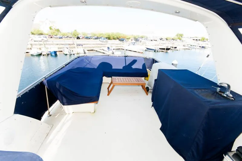 Slide: The Image of 1980 Hatteras 58 Motor Yacht deck with blue covers and wooden table at marina. - 46