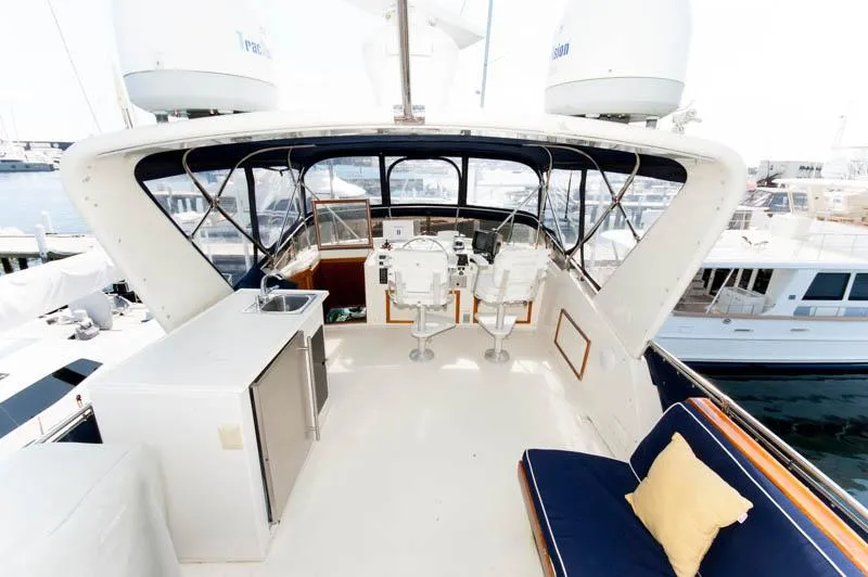 Slide: The Image of 1980 Hatteras 58 Motor Yacht flybridge with seating, helm, and marina view. - 47