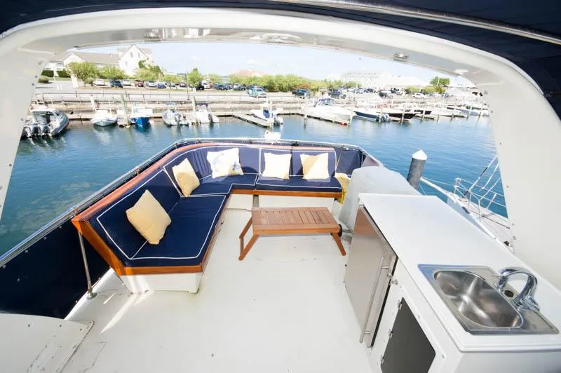 Slide: The Image of 1980 Hatteras 58 Motor Yacht deck with seating, table, and sink, overlooking marina. - 49