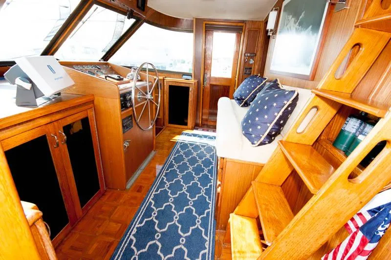 Slide: The Image of 1980 Hatteras 58 Motor Yacht interior with wooden helm, blue rug, and nautical decor. - 9