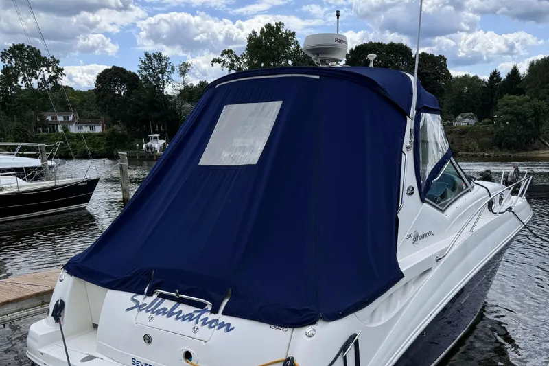 Slide: The Image of 2004 Sea Ray 320 Sundancer boat docked with blue cover, scenic marina background. - 5