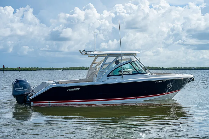 Slide: The Image of 2014 Pursuit DC 265 Dual Console boat on calm water under cloudy sky. - 38