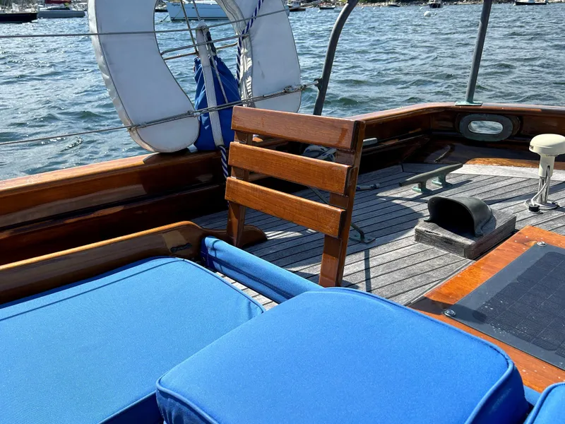 Slide: The Image of 1985 Herreshoff Nereia Molly's Cove 38' sailboat deck with blue cushions and wooden seating. - 26