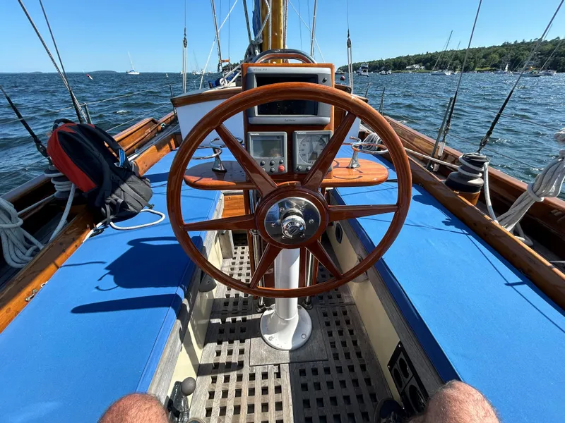 Slide: The Image of 1985 Herreshoff Nereia Molly's Cove 38' sailboat with FRP hull, wooden wheel, and blue seating. - 3