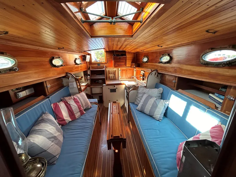 Slide: The Image of Interior of 1985 Herreshoff Nereia Molly's Cove 38' with FRP hull, featuring wooden finish and seating. - 5