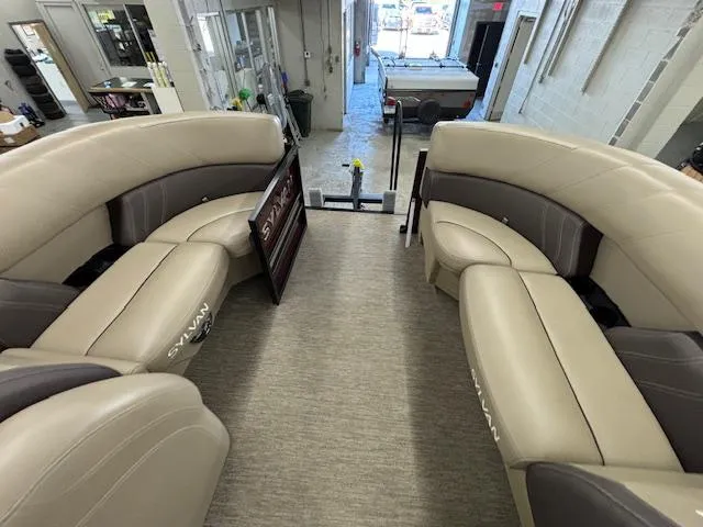 Slide: The Image of 2022 Sylvan Mirage X X3 pontoon boat interior with beige seating in a showroom. - 8