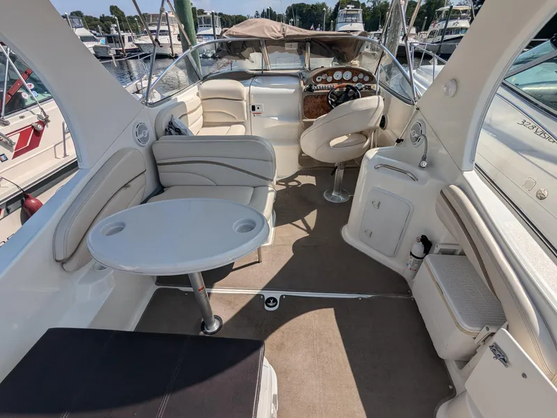 Slide: The Image of 2004 Larson Cabrio 260 boat interior with seating and steering wheel, docked at marina. - 12
