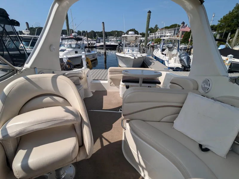Slide: The Image of 2004 Larson Cabrio 260 boat interior with beige seating at a marina. - 14