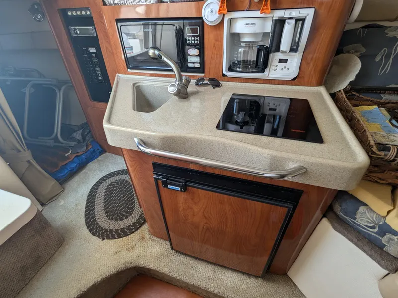 Slide: The Image of 2004 Larson Cabrio 260 boat kitchenette with sink, microwave, and coffee maker. - 17
