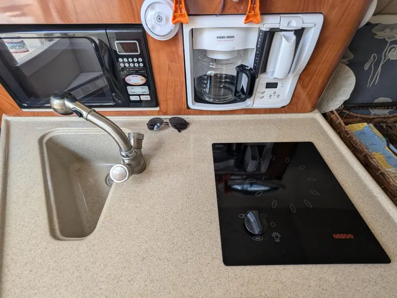 Slide: The Image of 2004 Larson Cabrio 260 kitchen with sink, stove, microwave, and coffee maker. - 19