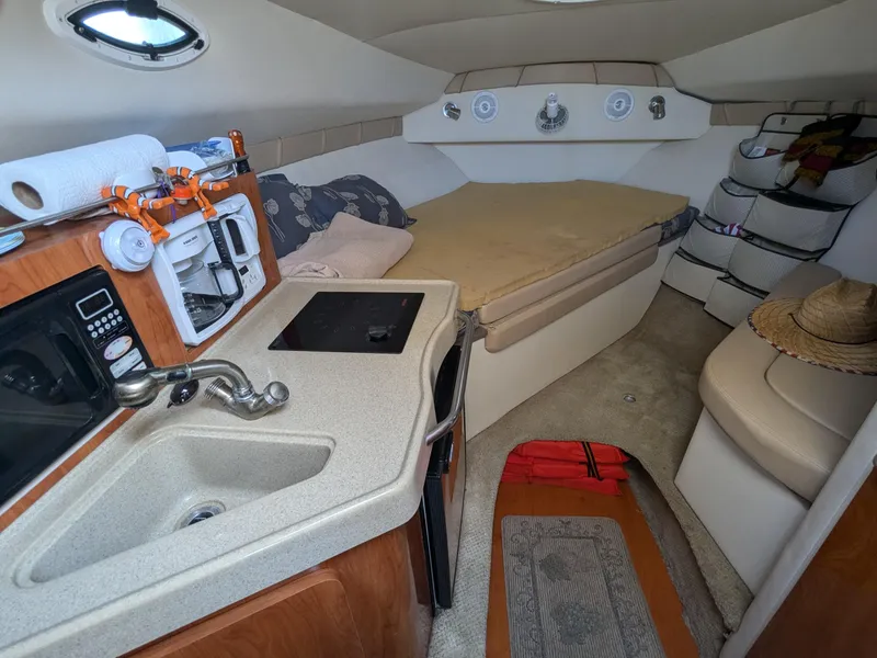 Slide: The Image of Interior of 2004 Larson Cabrio 260 boat with kitchenette and cozy sleeping area. - 23