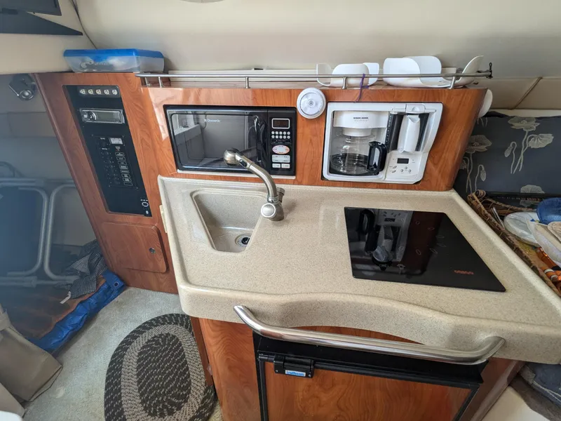 Slide: The Image of 2004 Larson Cabrio 260 boat kitchenette with sink, microwave, and coffee maker. - 24