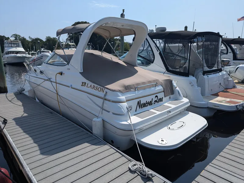 Slide: The Image of 2004 Larson Cabrio 260 boat docked at marina, covered with beige canopy. - 3