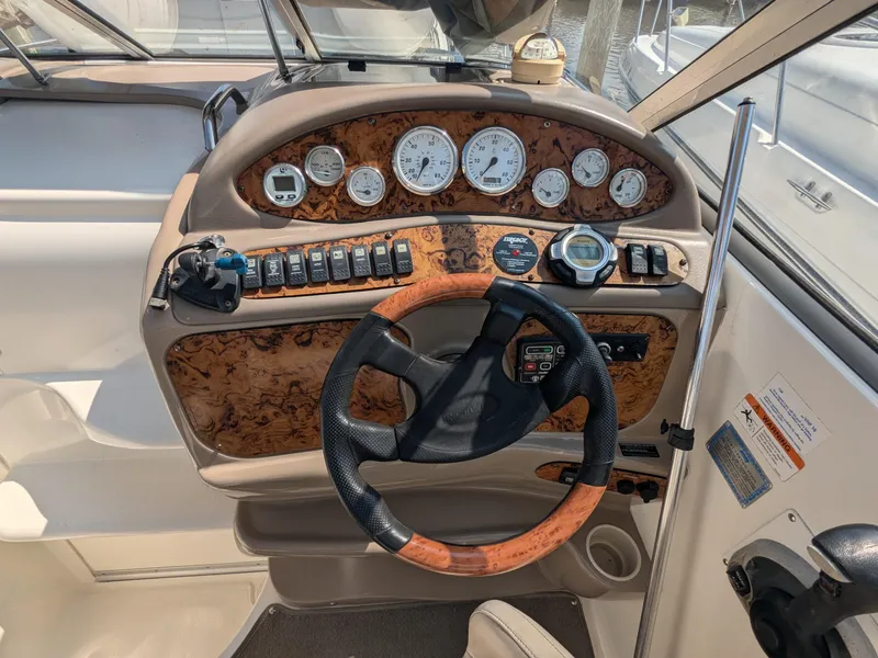 Slide: The Image of 2004 Larson Cabrio 260 boat dashboard with wood accents and steering wheel. - 6