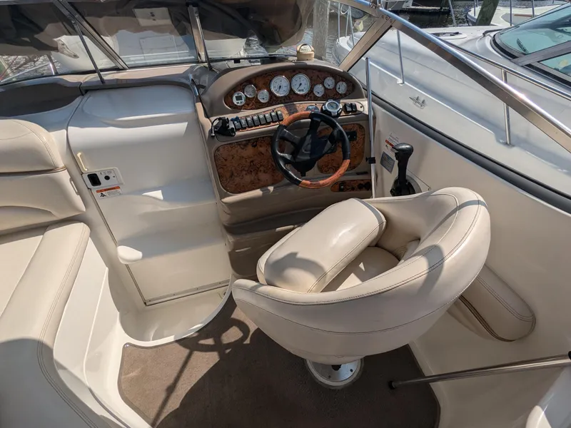 Slide: The Image of 2004 Larson Cabrio 260 boat interior with steering wheel and beige seating. - 7