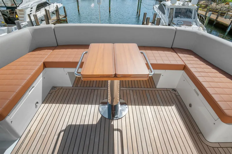 Slide: The Image of 2023 Astondoa AS5 yacht deck with cushioned seating and wooden table. - 18