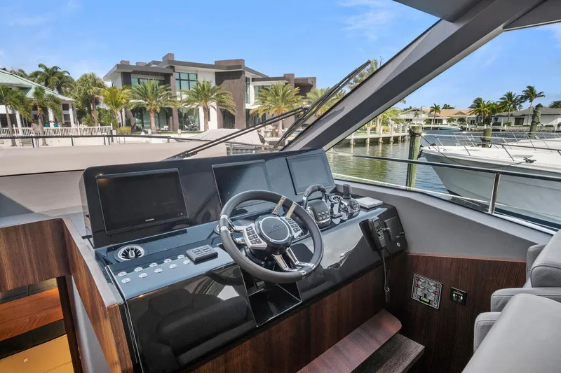 Slide: The Image of 2023 Astondoa AS5 yacht helm with modern controls, docked near luxury waterfront homes. - 29