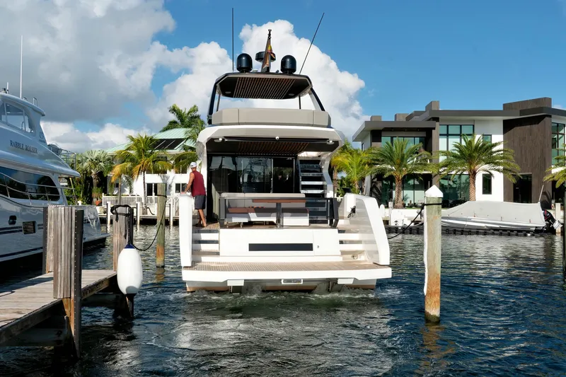 Slide: The Image of 2023 Astondoa AS5 yacht docked at a marina with palm trees and modern buildings. - 4