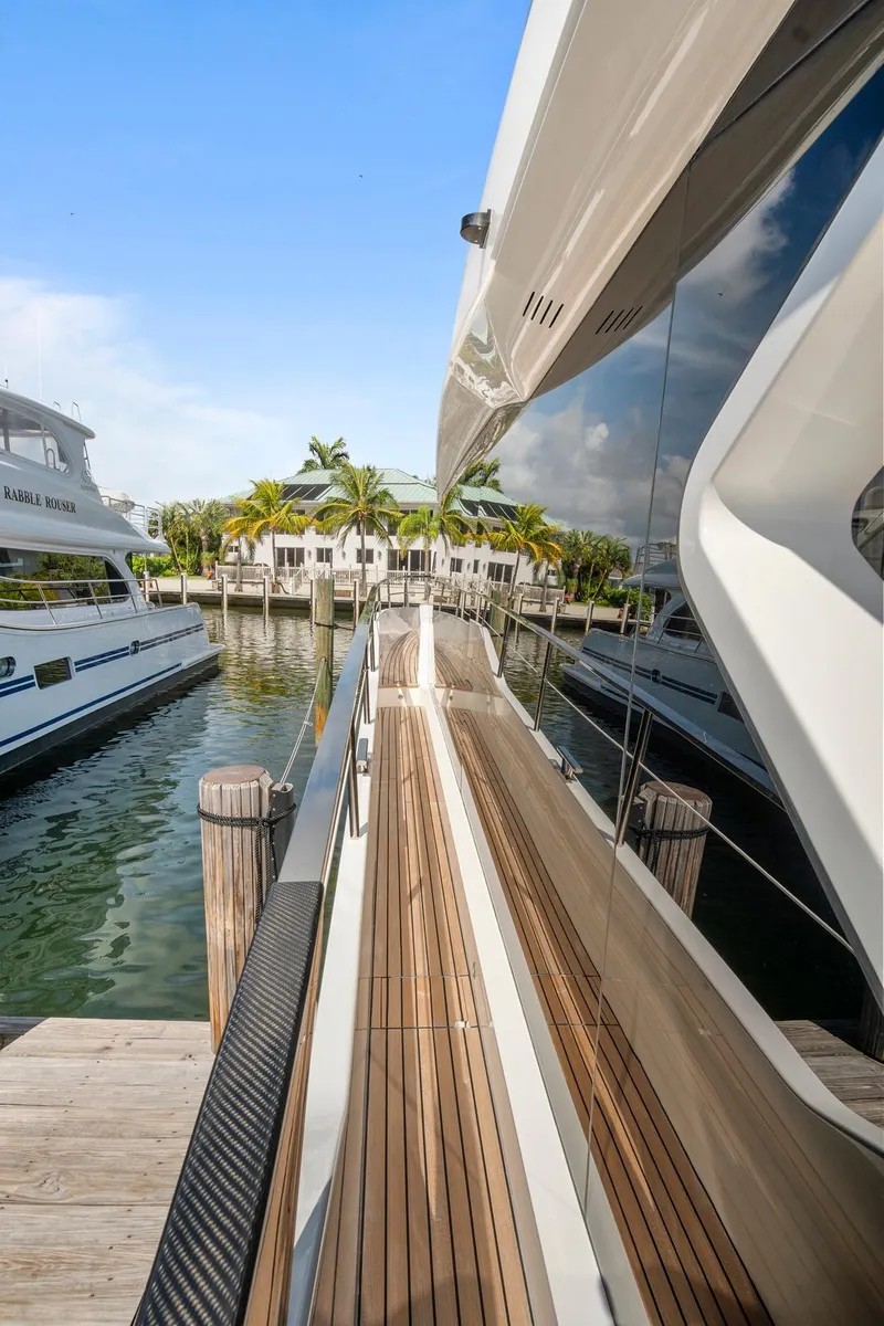 Slide: The Image of 2023 Astondoa AS5 yacht docked, featuring sleek design and wooden deck. - 8