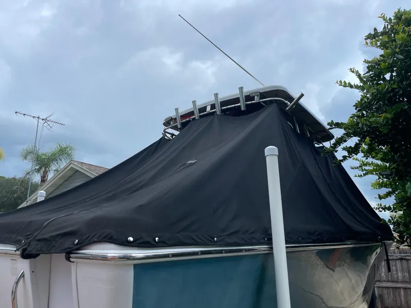 Slide: The Image of 2007 Pro-Line 25 Sport boat with black cover, parked outdoors under cloudy sky. - 18