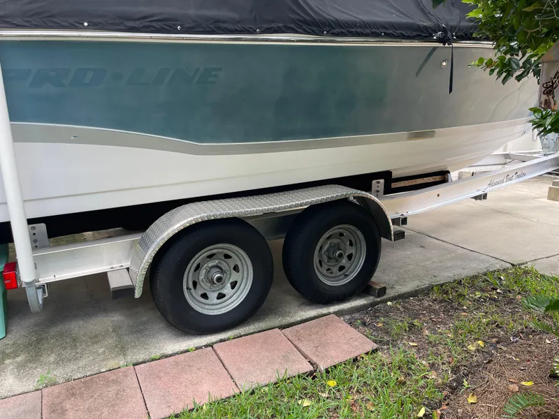 Slide: The Image of 2007 Pro-Line 25 Sport boat on trailer, partially covered, parked on driveway. - 2