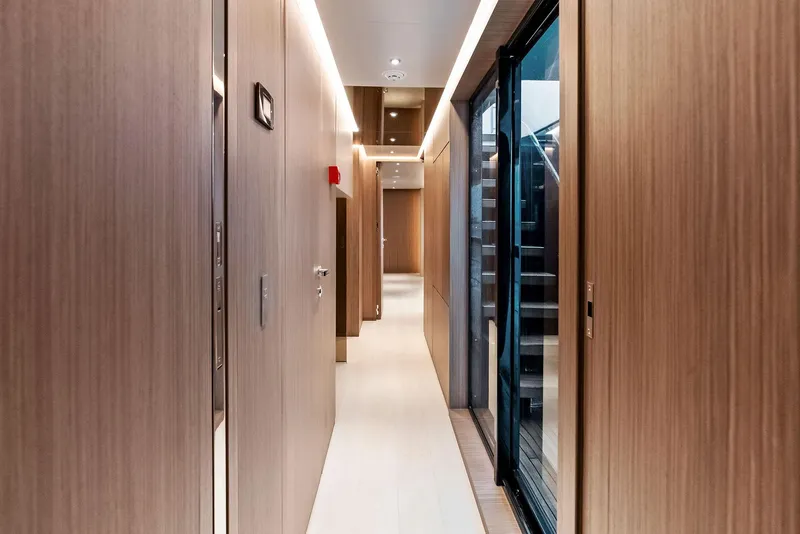 Slide: The Image of Luxurious interior hallway of 2023 Custom Line 106' yacht, featuring sleek wood paneling. - 26