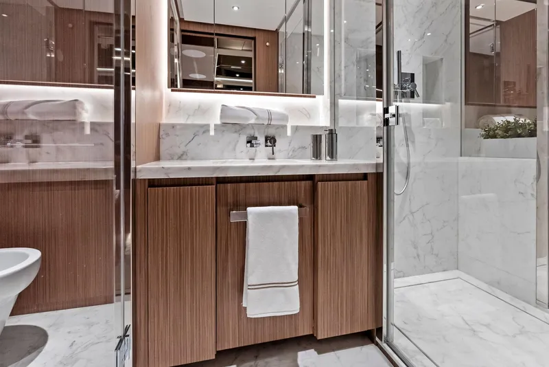Slide: The Image of Luxurious yacht bathroom with marble accents, modern fixtures, and wooden cabinetry, 2023 Custom Line 106'. - 31