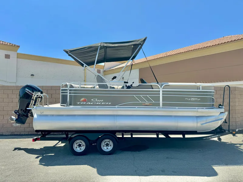 The Image of 2023 Sun Tracker Party Barge 20 DLX pontoon boat on trailer, parked outdoors. - 1