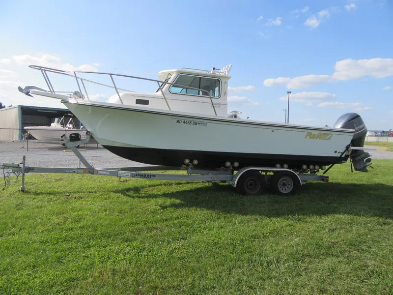 Slide: The Image of 2018 Parker 2320 SL Sport Cabin boat on trailer, parked on grass under blue sky. - 3