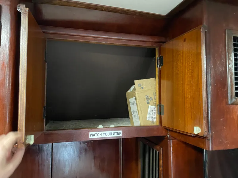 Slide: The Image of Open wooden cabinet on 1986 Post 43 Sport Fisher boat with a box inside. - 24