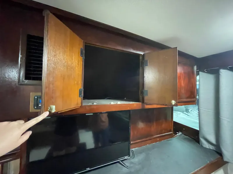 Slide: The Image of Interior of 1986 Post 43 Sport Fisher with open wooden cabinets and a mounted TV. - 25