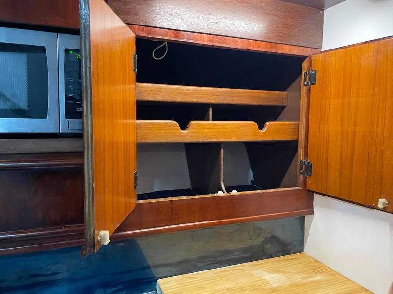 Slide: The Image of 1986 Post 43 Sport Fisher kitchen cabinet with open wooden doors and microwave. - 35