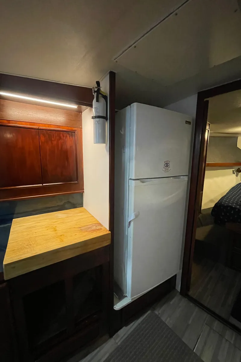 Slide: The Image of 1986 Post 43 Sport Fisher interior with fridge and wooden cabinetry. - 36