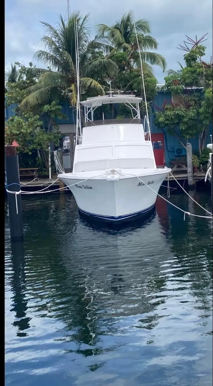 Slide: The Image of 1986 Post 43 Sport Fisher boat docked, surrounded by palm trees and calm water. - 4